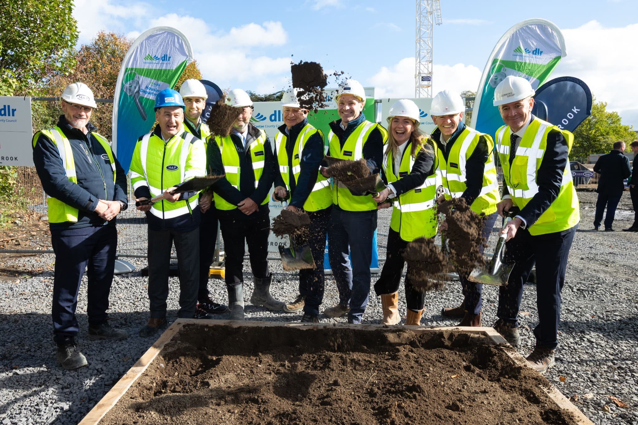 Attendees toss soil from their spades during the Emmet Gardens sod-turning celebrations.